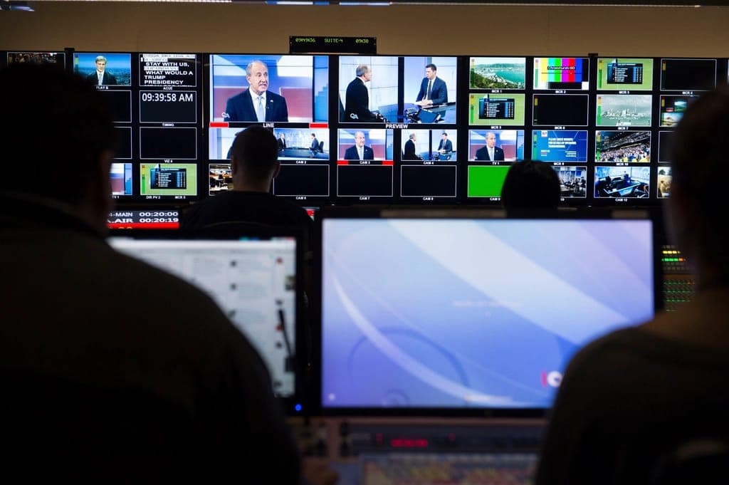 Producers working in front of a wall of broadcast monitors
