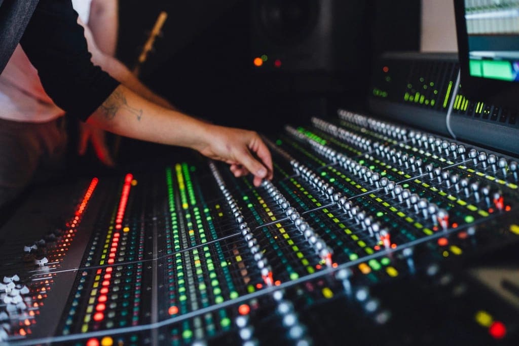 Hands adjusting faders on a mixing console